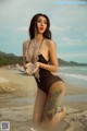 A woman in a black bathing suit sitting on a beach.