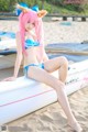 A woman in a bikini sitting on a surfboard on the beach.